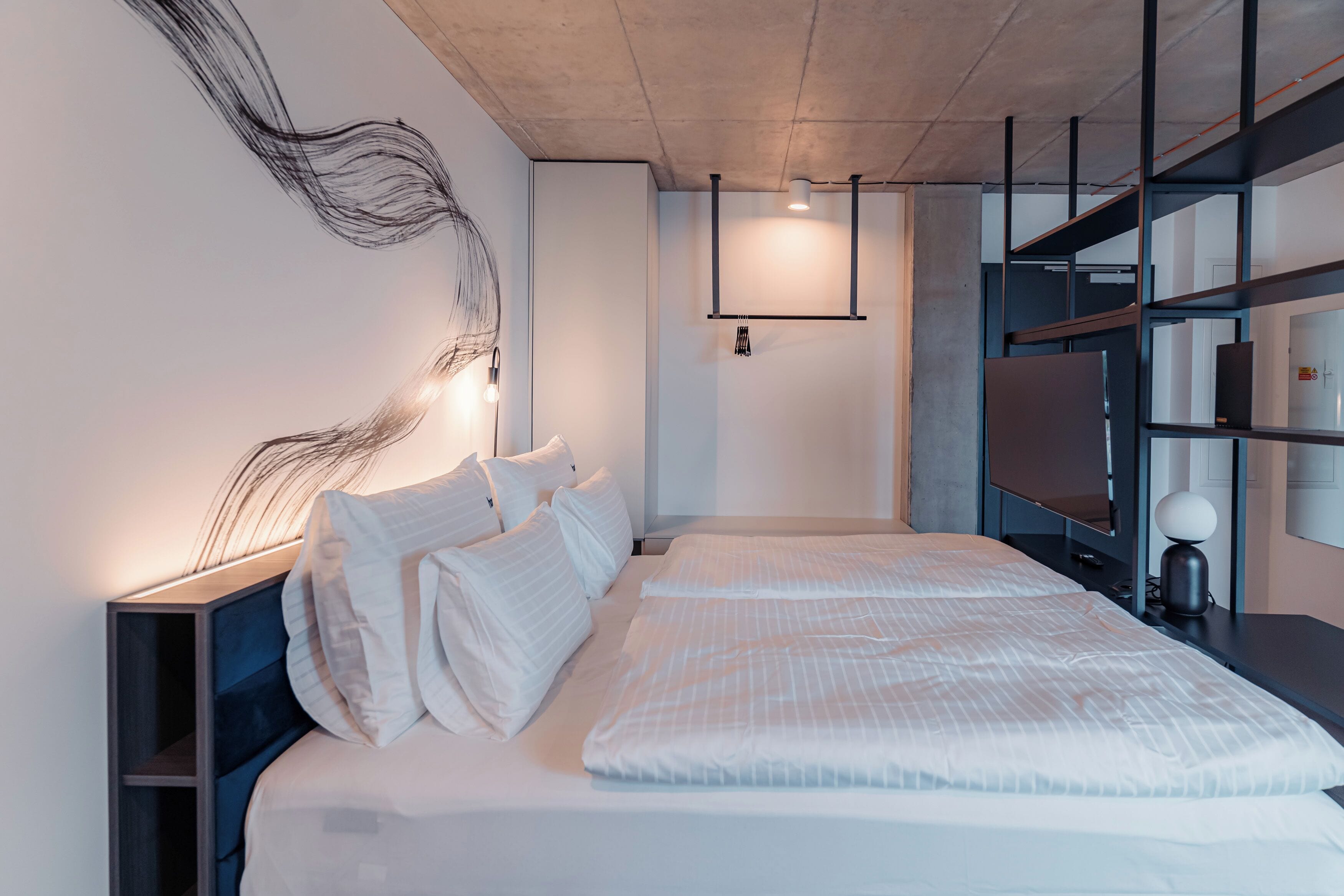 Une chambre d’hôtel moderne, dotée d’un grand lit, d’un bureau et d’un téléviseur intégré.