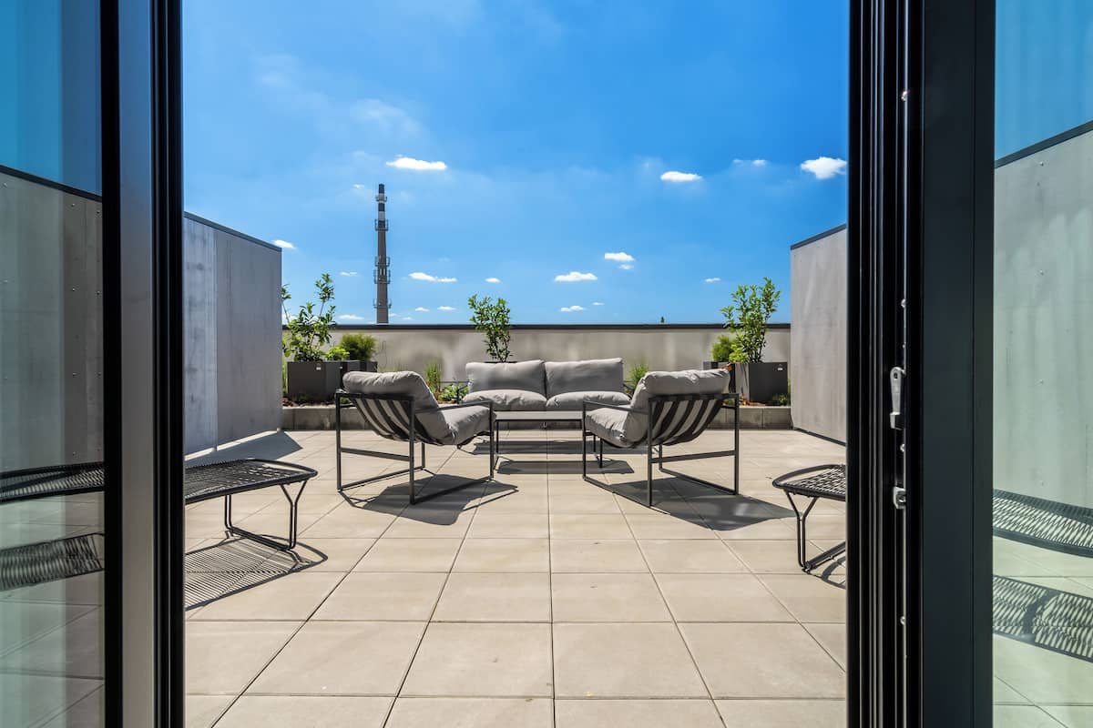 A patio area with a sofa and chairs, a small table, and potted plants.