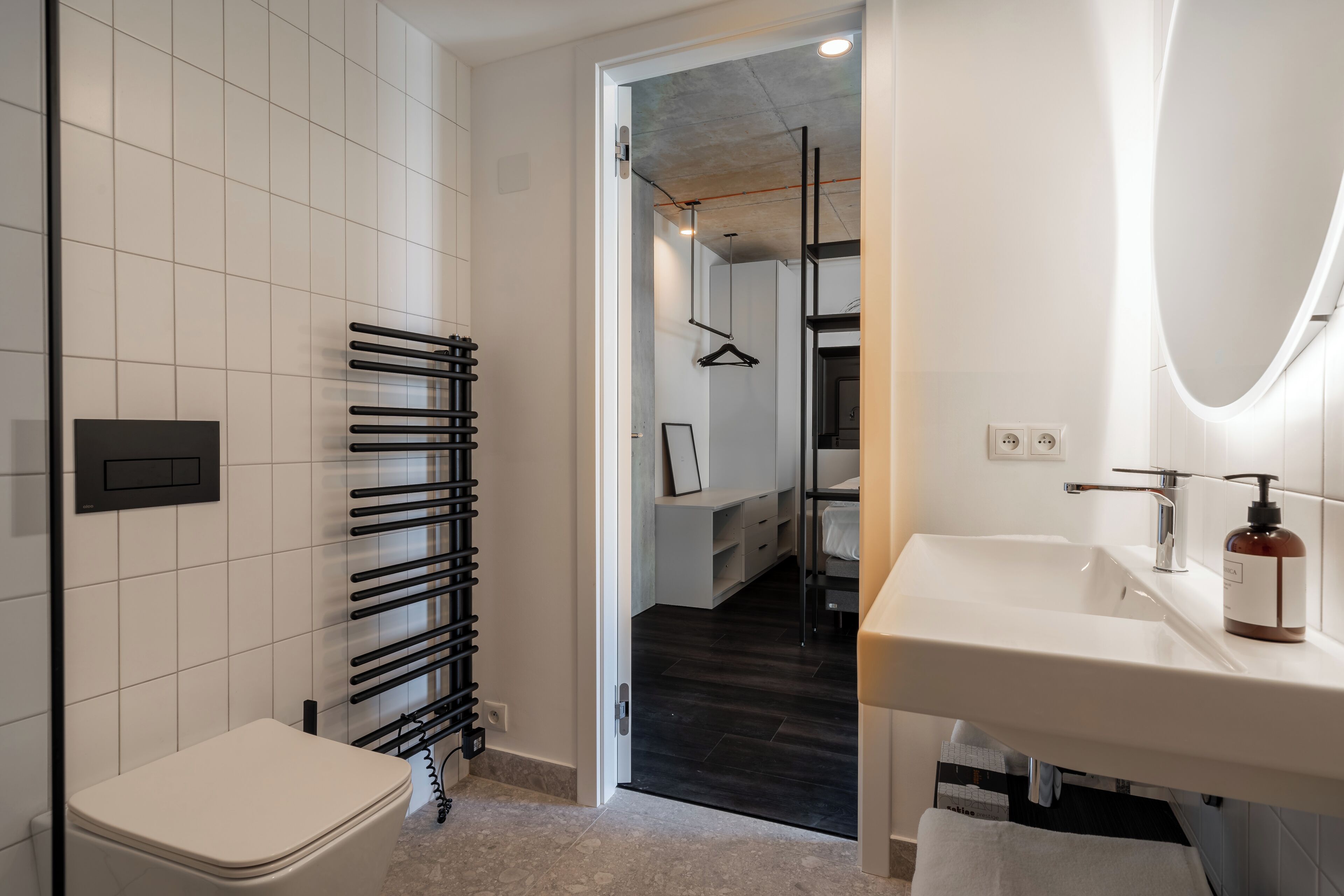 A modern bathroom with a white sink, a toilet, and a towel rack.