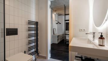 A modern bathroom with a white sink, a toilet, and a towel rack.