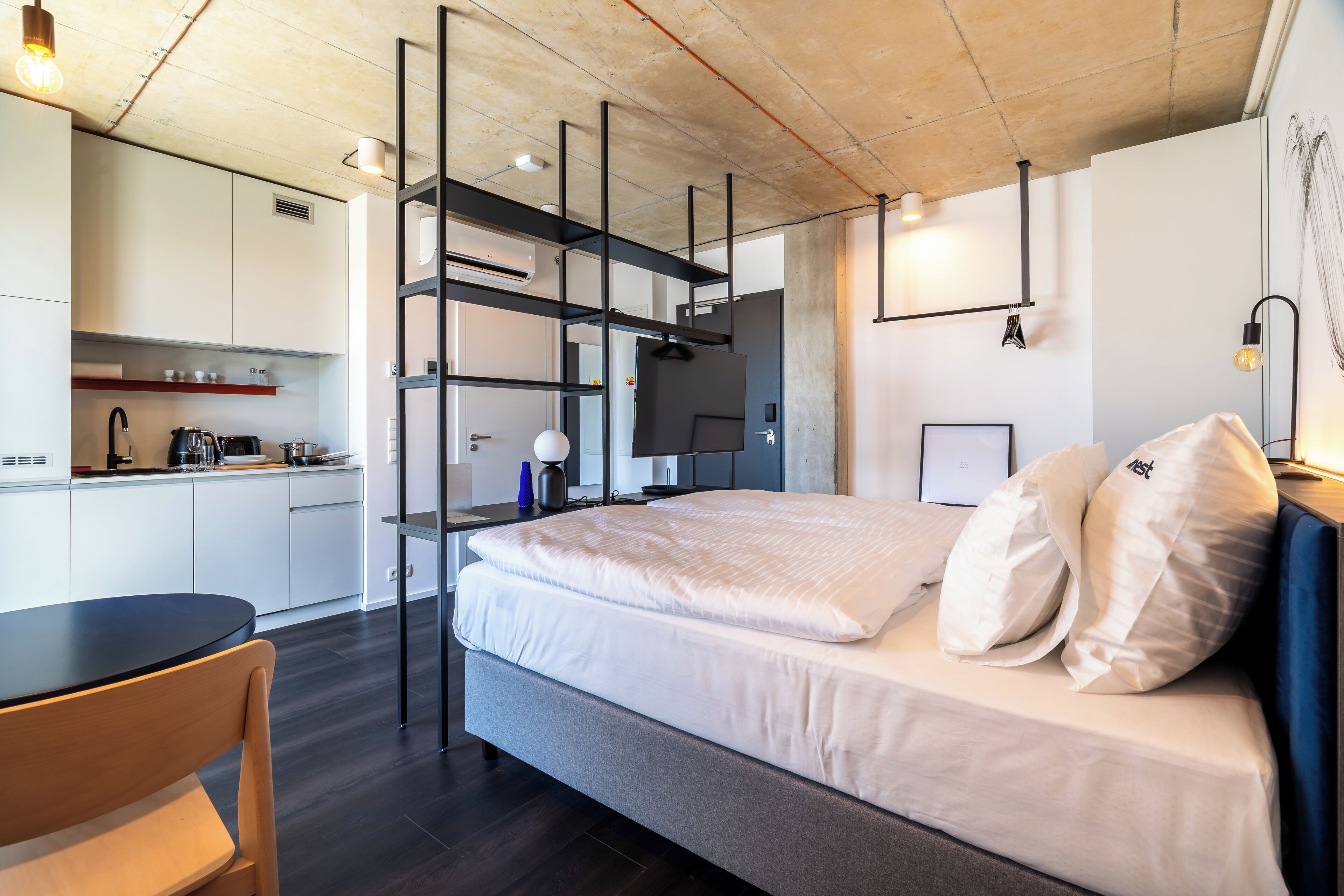 Ein modernes Hotelzimmer mit Bett, Schreibtisch und einer Küchenzeile.