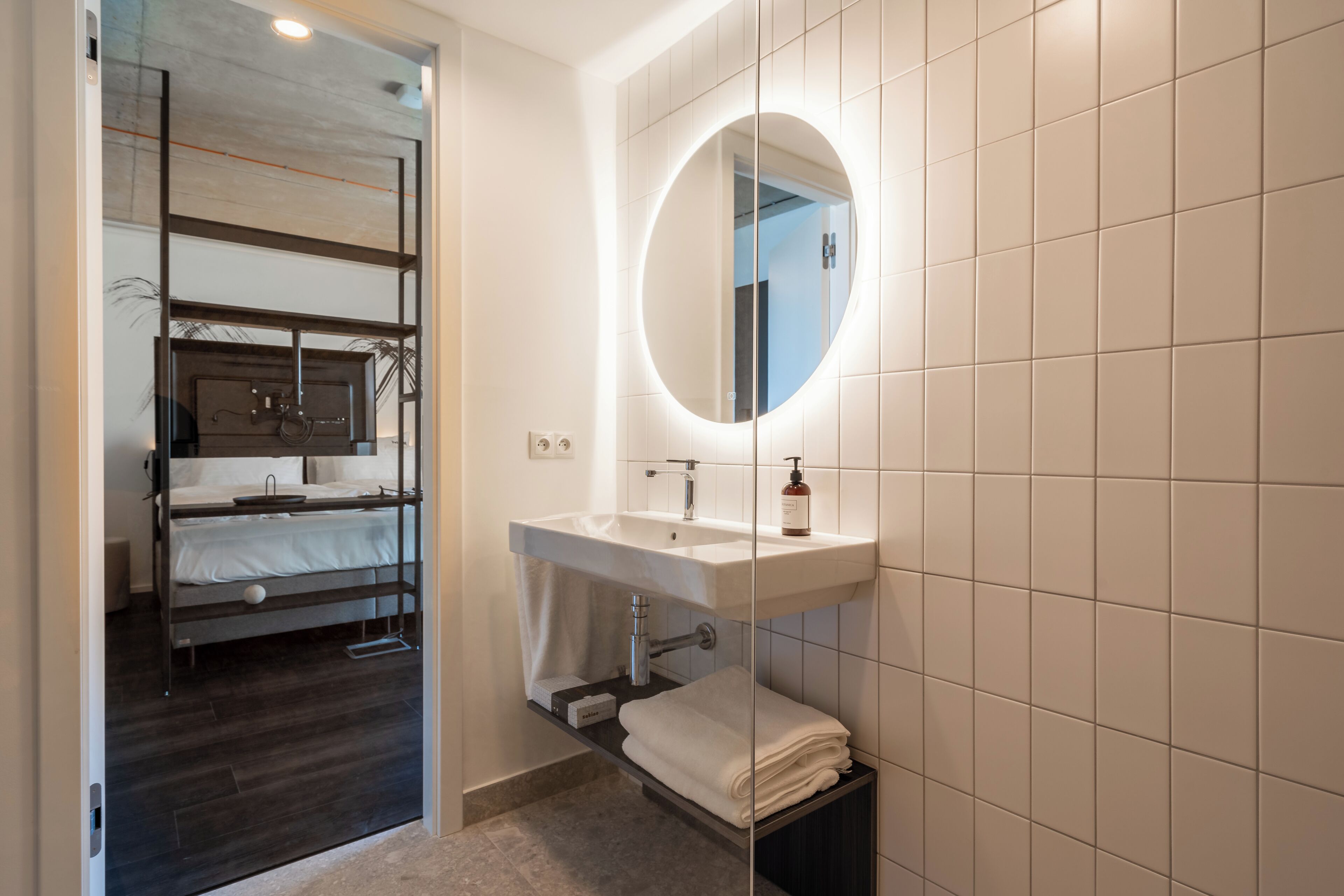 A modern bathroom with a built-in sink, a round mirror, and a towel rack.