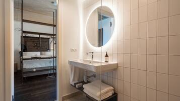 Ein modernes Badezimmer mit integriertem Waschbecken, einem runden Spiegel und einem Handtuchhalter.