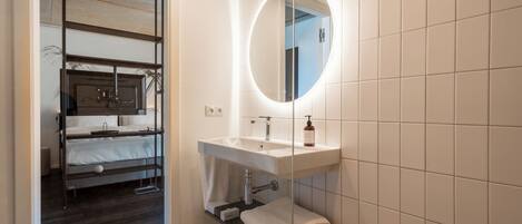 A modern bathroom with a built-in sink, a round mirror, and a towel rack.