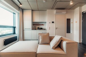 Una habitación moderna con sofá, ventana, kitchenette y puerta.
