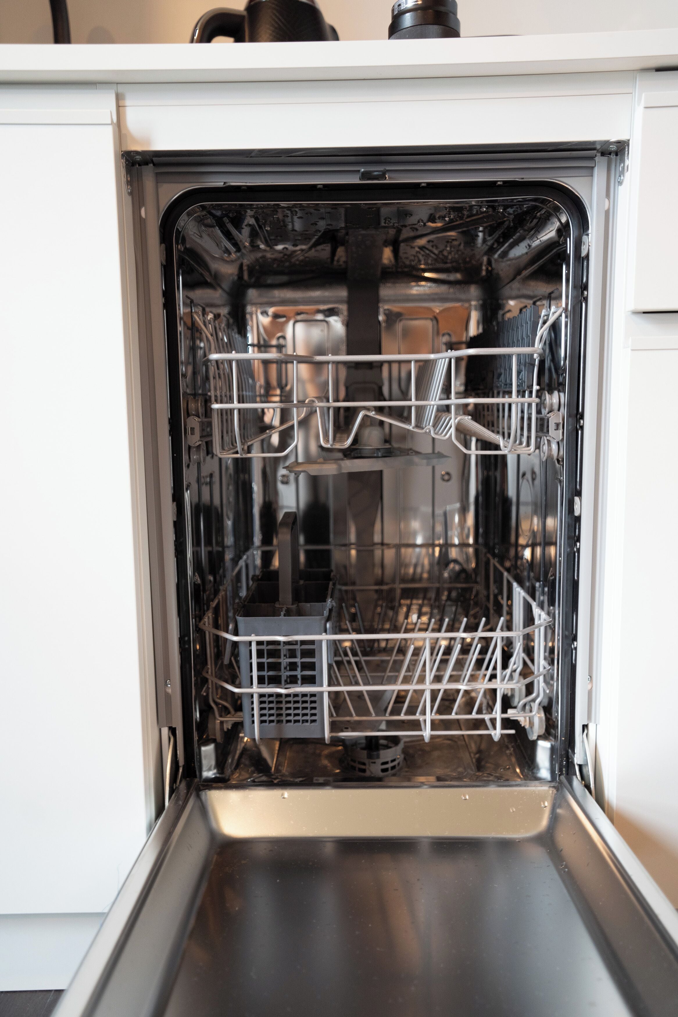 Un lave-vaisselle ouvert, avec ses étagères et son panneau de commande.