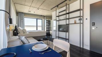 A modern, compact living space with a sofa, dining table, and built-in TV.