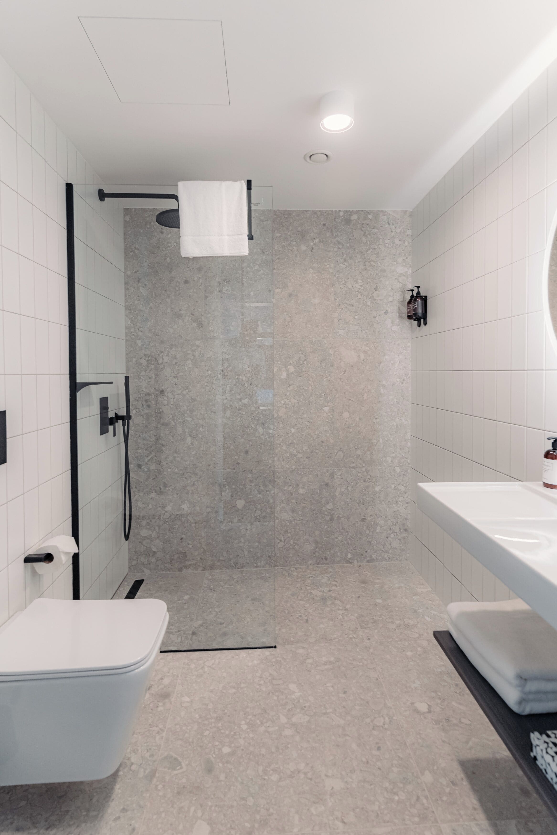 Een moderne badkamer met douche, toilet en wastafel.