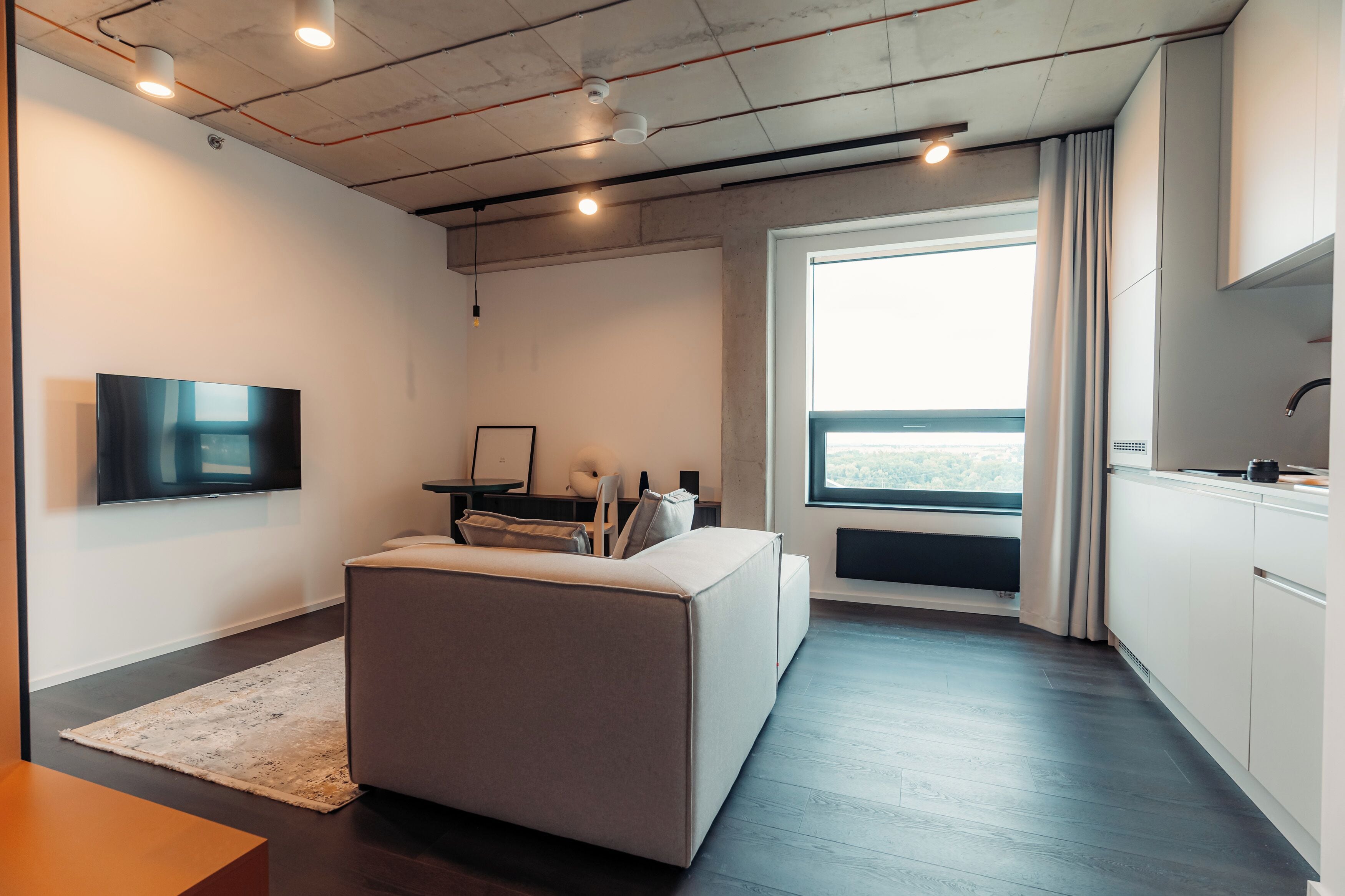 A modern room with a sofa, a TV, a desk, and a window with a view.