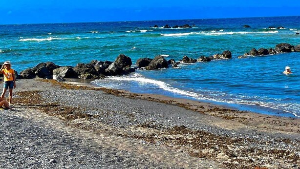 A rocky beach with clear blue water and a person standing on the shore. - Spacious loft in the heart of a quiet and lively beach town.  (Arona)