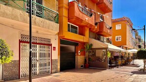 A street view with a building featuring a gated entrance, outdoor seating area, and a visible restaurant. - Spacious loft in the heart of a quiet and lively beach town.  (Arona)