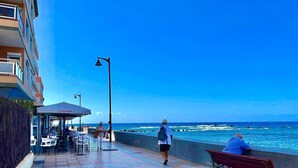 A coastal walkway with outdoor seating, a covered area, and a view of the ocean. - Spacious loft in the heart of a quiet and lively beach town.  (Arona)