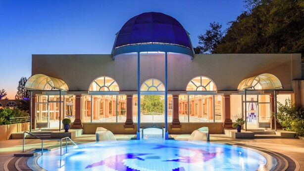 A modern hotel with a central pool, arched windows, and a dome structure.