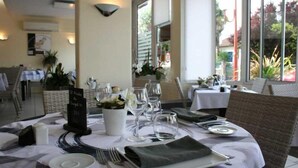 A restaurant table set with plates, glasses, and cutlery, with a menu stand and a vase of flowers.