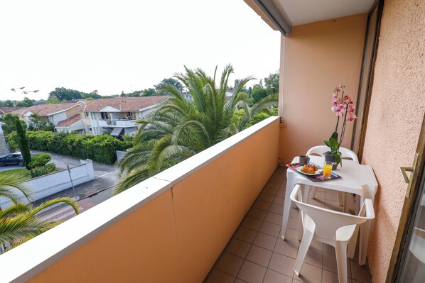 A balcony with a table and chairs, a potted plant, and a view of the neighborhood. - TERRASSES DE BORDA (Dax)