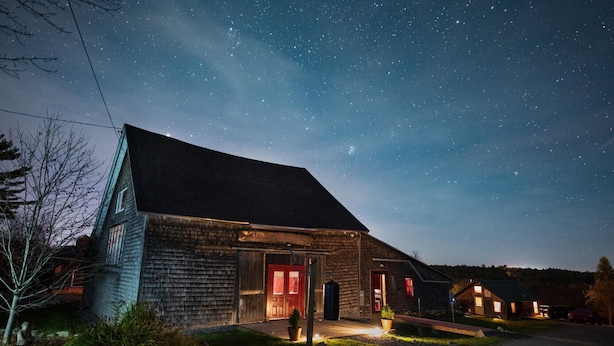 A rustic building with a sloped roof, a red door, and a small porch area. - Cozy Cottage (Surry)