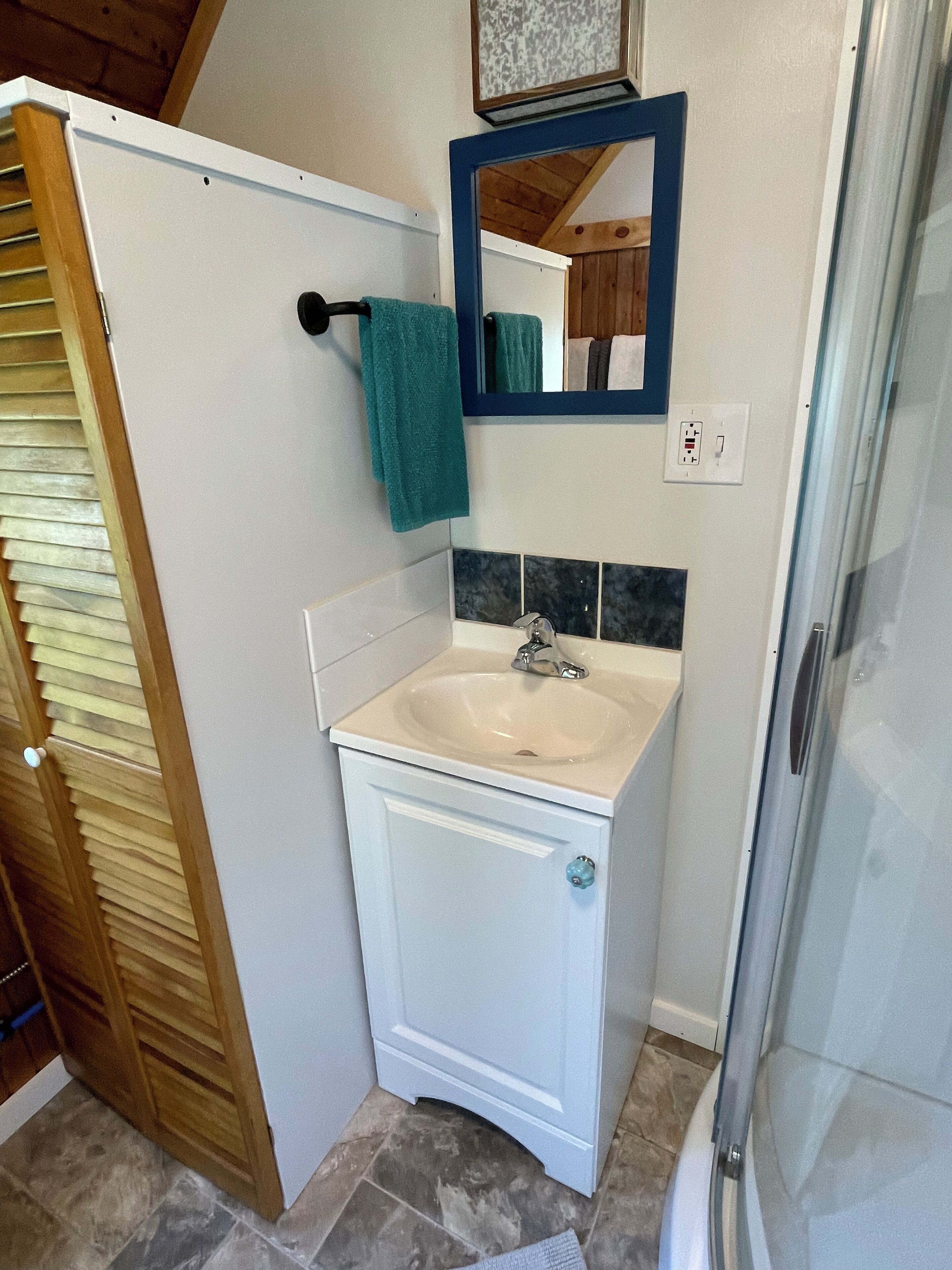 Ein Badezimmer mit einem weißen Waschbecken, einem Spiegel und einer Dusche.