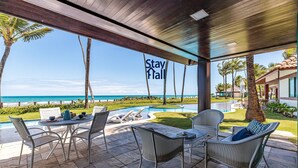 A covered outdoor seating area with a pool, lounge chairs, and a view of the ocean. - Bangalô 4qts BeiraMar em Muro Alto-SH034 (Ipojuca)