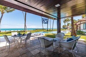 Un espace extérieur aménagé, abrité et doté d’une piscine, de chaises longues et offrant une vue sur l’océan.