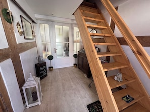 Una escalera de madera lleva a un rellano con una puerta blanca y ventanas con vidrio esmerilado.