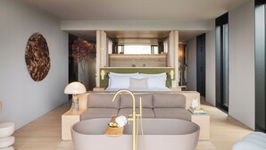 Une chambre à coucher moderne avec une grande baignoire, un canapé et une table de chevet avec une lampe.