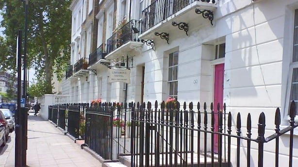 A row of white buildings with black railings and a pink door. - Oban Victoria Hotel (London)