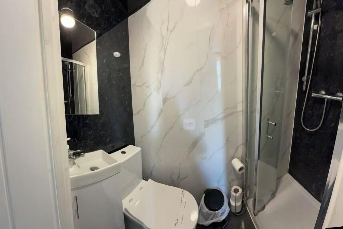 Un baño moderno con lavamanos blanco, inodoro y zona de ducha con mampara de cristal.