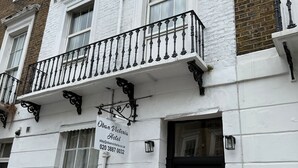 A white building with a black iron balcony and a black door. A sign on the building reads "Oban Victoria Hotel." - Oban Victoria Hotel (London)