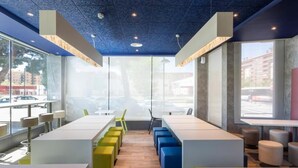 A modern restaurant with high ceilings, large windows, and colorful seating. - B&B HOTEL Zaragoza Plaza Mozart  (Zaragoza)