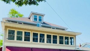 A two-story building with a flat roof, large windows, and a purple awning.