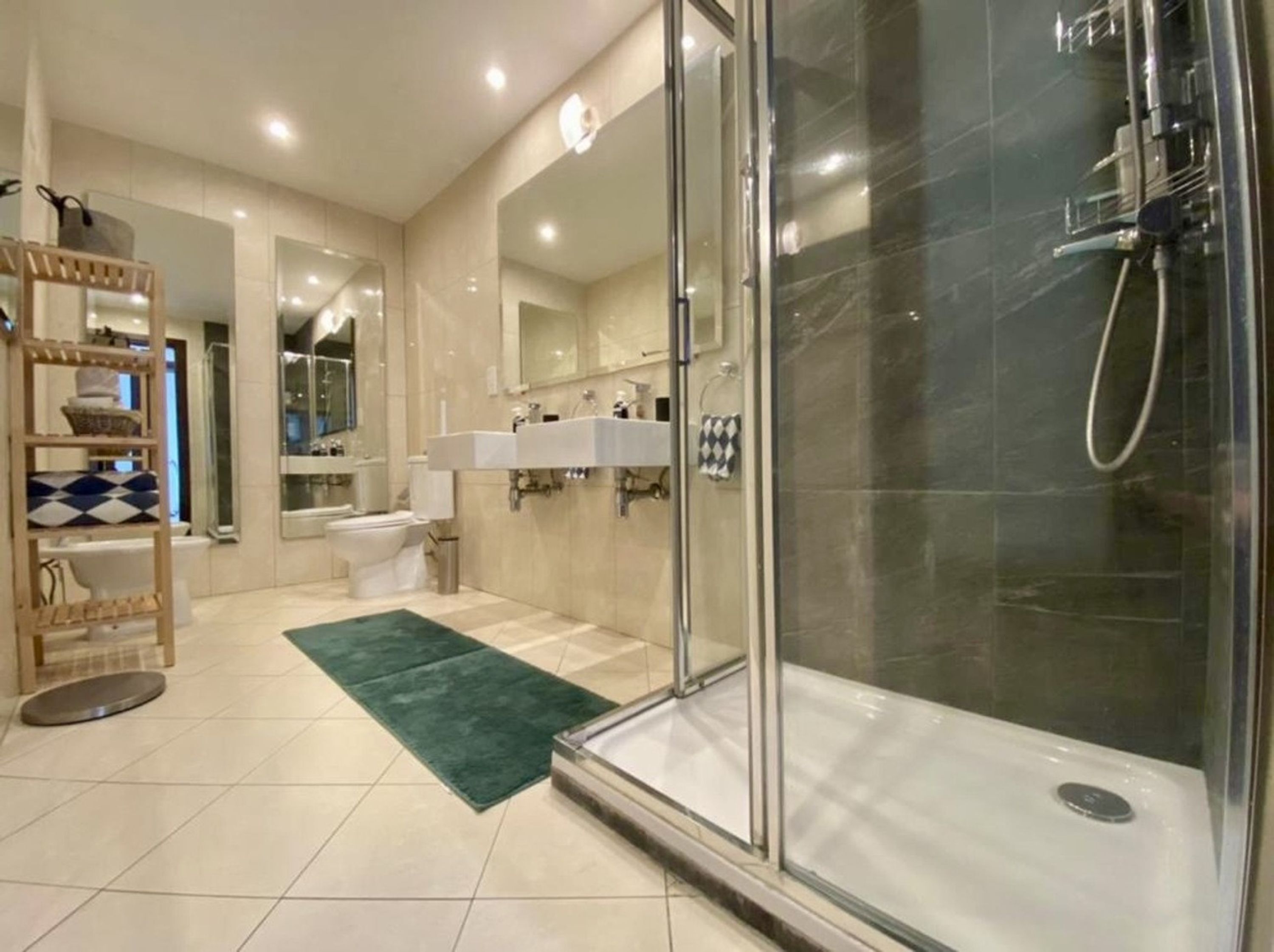 A modern bathroom with a glass-enclosed shower, a toilet, and a sink.