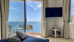 Una habitación con cama, televisión y vista al océano.