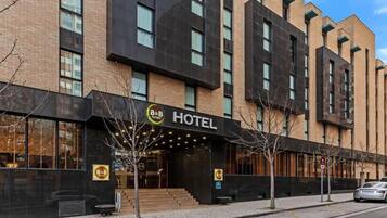 A modern hotel with a prominent entrance, a B&B logo, and a staircase leading to the lobby.