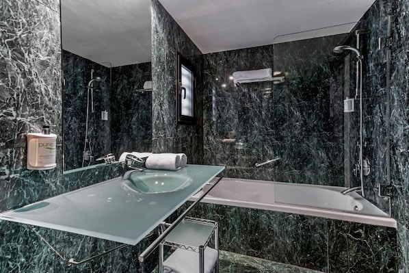 Une salle de bain moderne avec un lavabo en verre, une baignoire et un espace douche.