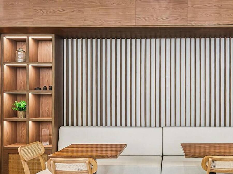 A modern interior with a wooden panel wall, a white sofa, and two small tables.