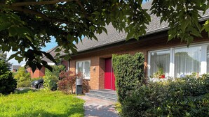 Ein Wohnhaus mit roter Tür, Ziegelaußenwand und einem Weg zum Eingang.