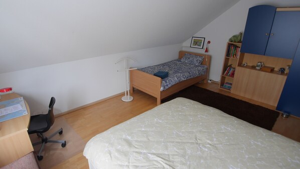 A small, tidy room with a single bed, a desk with a chair, a bookshelf, and a wardrobe. - Hausnah (Bad Bentheim)