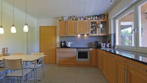 Eine moderne Küche mit Holzausstattung, einem Backofen, einer Kaffeemaschine und einem Fenster mit Blick auf ein Backsteingebäude.