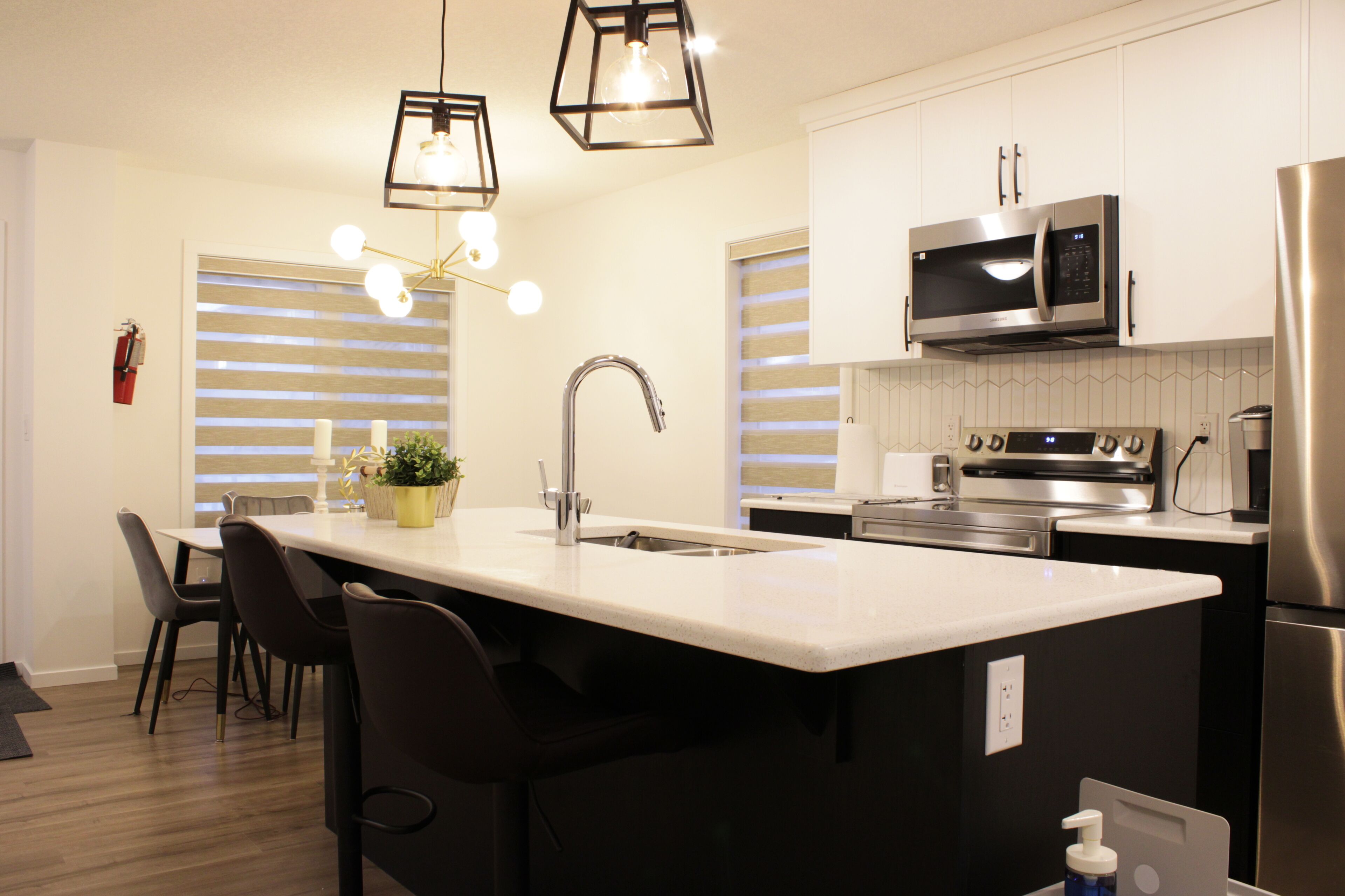 A modern kitchen with a central island, stainless steel appliances, and pendant lighting.
