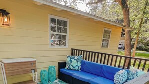 Une terrasse avec un canapé bleu, un banc en bois et un tapis à motifs.