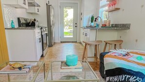 Un espace de vie compact comprenant un coin cuisine, un canapé, une table basse et un tapis à motifs.