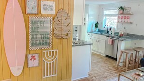 Un salon décoré sur le thème de la plage, avec une planche de surf, un panneau indiquant « Rendez-vous sur la plage » et un autre panneau indiquant « L’onde de la créativité ».