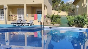 A swimming pool with lounge chairs and a covered area with a view of the surrounding landscape. - Mercury (Peniscola)