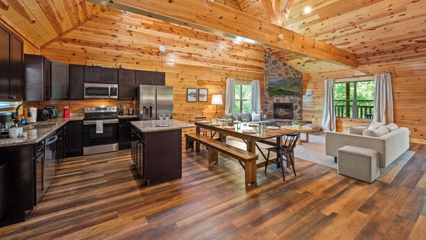 Un intérieur spacieux de chalet en bois, comprenant une cuisine, un coin repas et un salon.