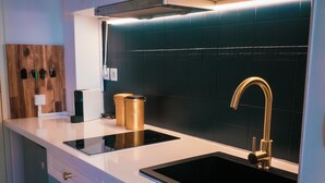 A modern kitchen with two black sinks, a gold faucet, and a wooden wall-mounted knife rack. - Modern Apartment with Sunny Terrace and Sea View (La Possession)