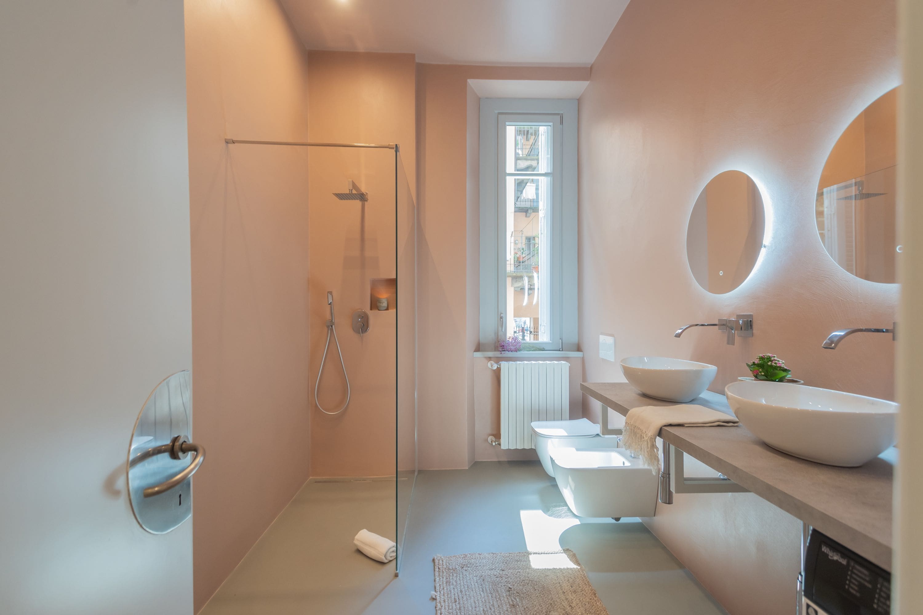 Un baño moderno con cabina de ducha de vidrio, un lavabo blanco y un espejo grande.