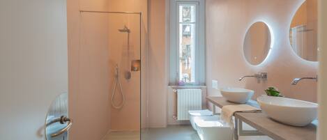Un baño moderno con cabina de ducha de vidrio, un lavabo blanco y un espejo grande.