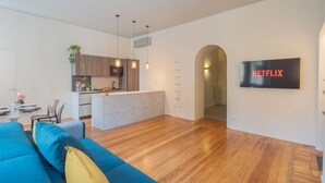 A modern living space with a kitchen, dining area, and a TV mounted on the wall. - Como Liberty Suites - Garbo (Como)