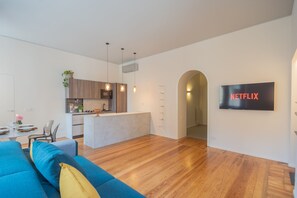 A modern living space with a kitchen, dining area, and a TV mounted on the wall. - Como Liberty Suites - Garbo (Como)