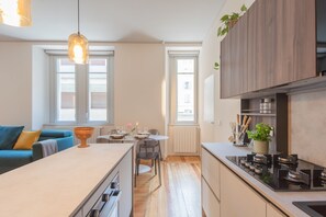 Une cuisine moderne dotée d’un îlot central, de meubles en bois et d’un coin repas avec une table dressée pour deux personnes.